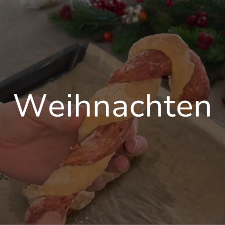 Link zur Seite "Weihnachten". Auf dem Bild: Eine Hand hält eine gebackene Zuckerstange.